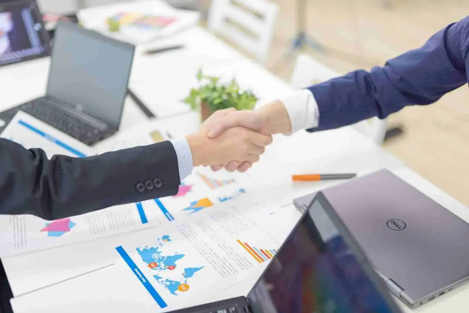 病院経営の計画を立てる医師の手元。デスクの上にはカレンダー、グラフ資料、ノートパソコン、計算機が並んでいる。